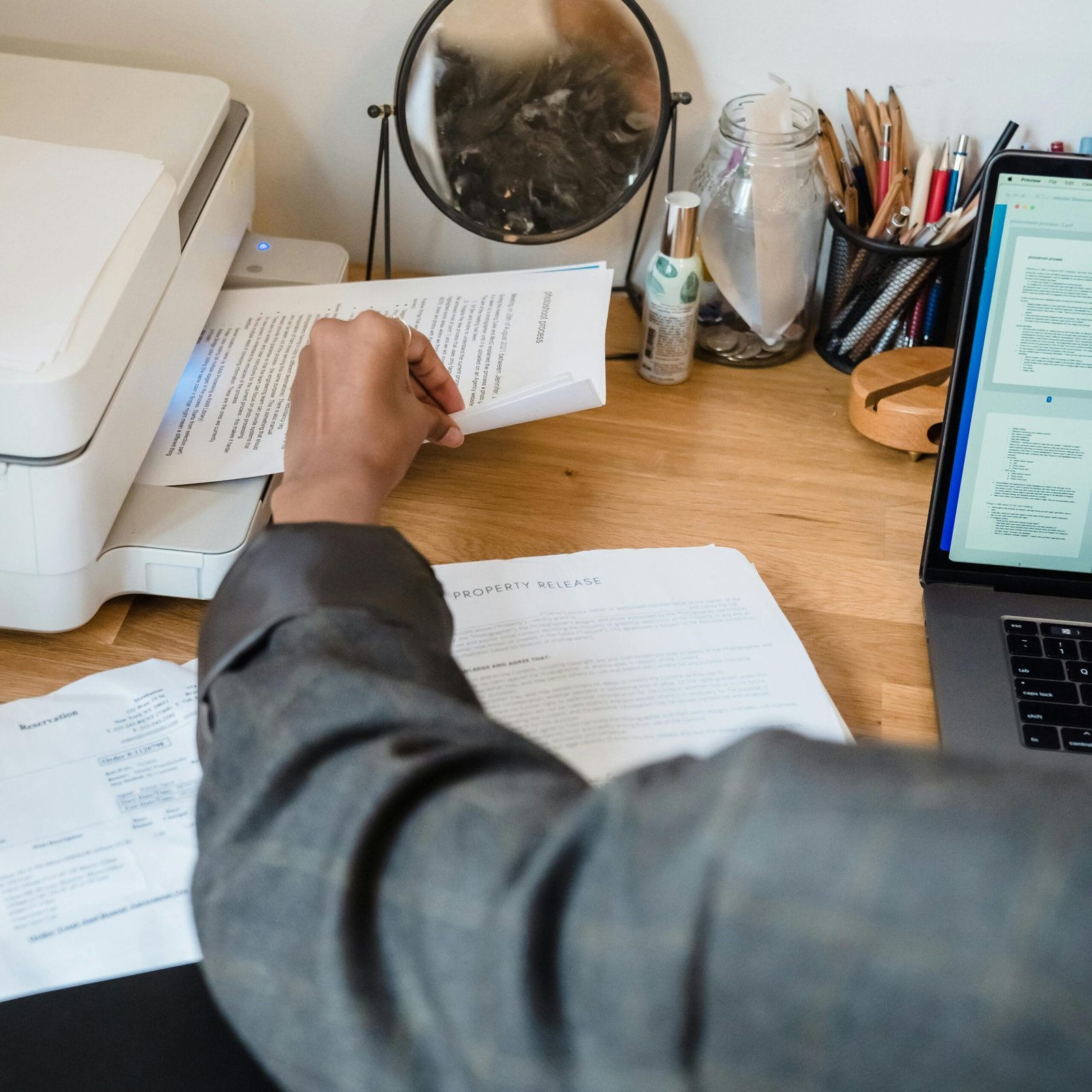 Focused professional working on documents with laptop and printer nearby.