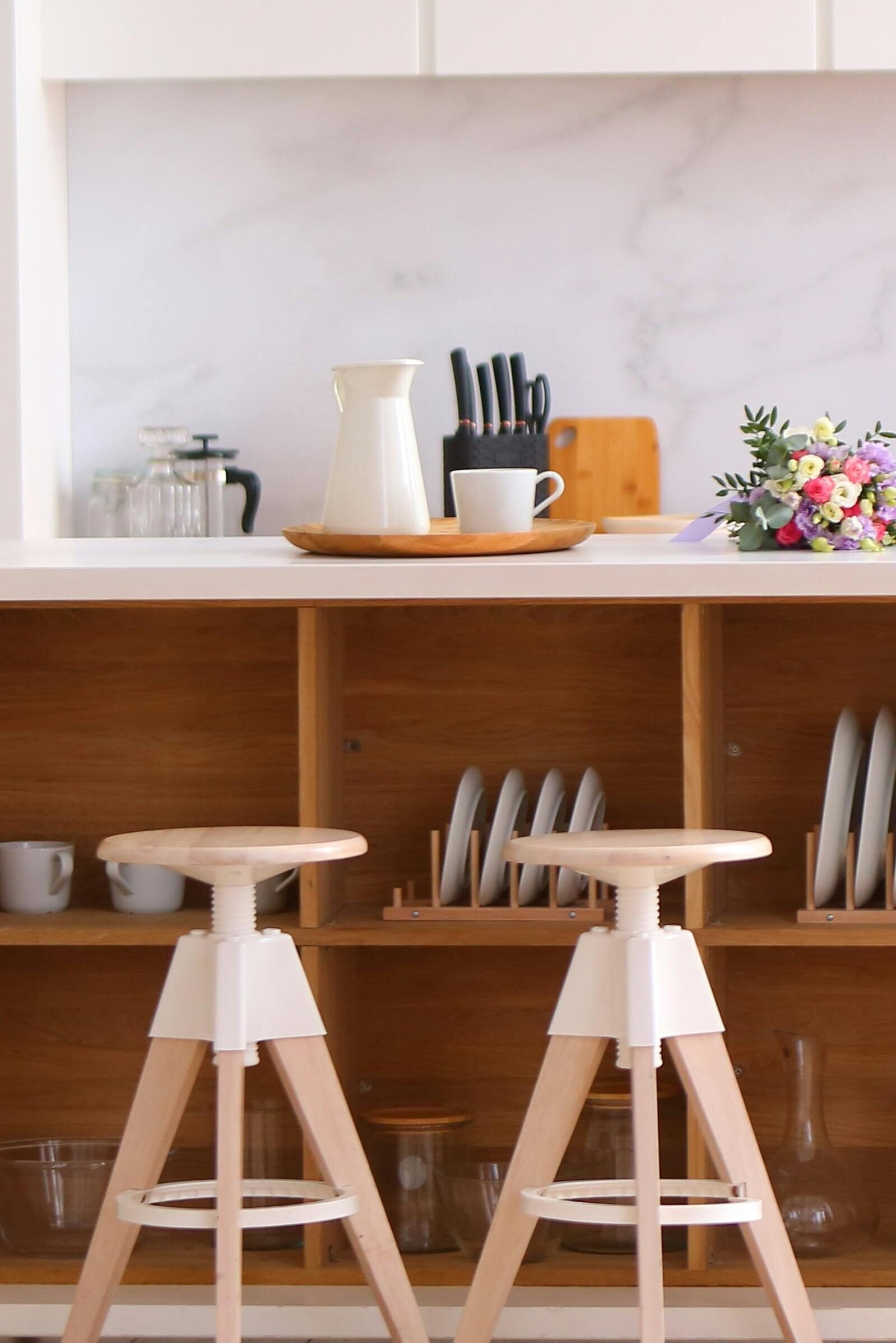 Elegant kitchen interior featuring wooden stools and organized shelves, perfect for contemporary home design.